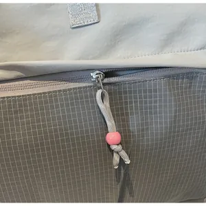 Détail du sac de voyage gris avec broderie STTCA et fermeture éclair métallique à perle