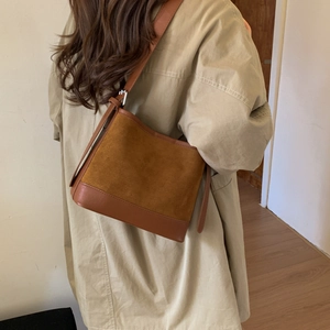 Detail of a brown patchwork shoulder bag featuring suede and smooth leather textures