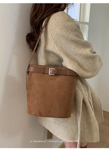 Détail d'un sac seau en daim marron avec boucle rétro et accessoires en argent poli