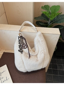 Close-up of white plush tote bag featuring decorative bingo charms and textured fur