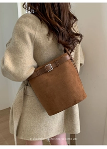 Détail du sac seau en daim marron foncé avec boucle de ceinture sur manteau