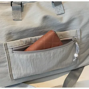 Détail de la poche avant zippée sur sac de voyage gris montrant sa capacité de rangement