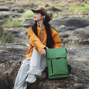 Scène de plein air avec sac à dos de randonnée vert, veste orange et chapeau sur les rochers