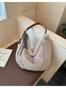 Detail of soft beige faux fur tote bag with leather strap and decorative letter charm
