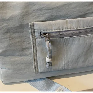 Détail de la poche à fermeture éclair sur un sac de voyage bleu avec tirette tressée