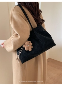 Detail of black matte tote bag featuring a cute plush bear pendant and tassel decor