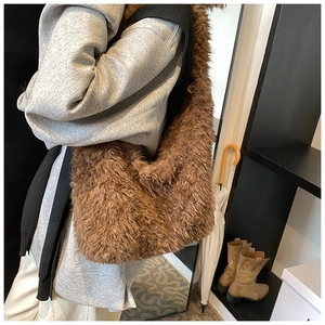 Close-up of fluffy brown plush bucket bag shown on model for shoulder wear
