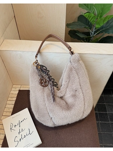 Detail of plush faux fur tote bag with leather handle and decorative charm pendant