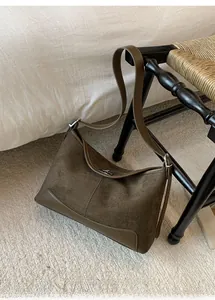 Detailed close-up of dark brown suede shoulder bag with silver metal twist lock closure