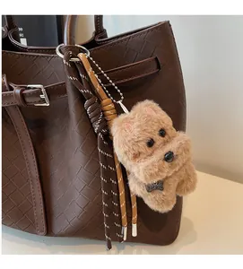 Close-up of plush dog charm with metal Top Dog tag and woven rope on tote bag