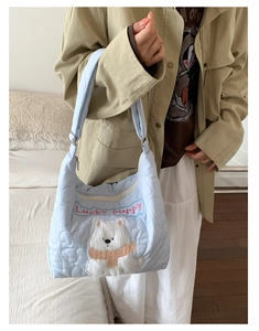 Détail du sac fourre-tout matelassé bleu clair avec écusson Lucky Puppy et cœurs