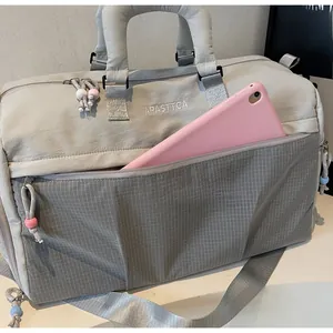 Détail du sac de voyage gris avec poche en filet et tablette rose à l'intérieur