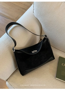Close-up of black matte leather shoulder bag featuring a silver metal turn-lock buckle