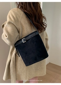 Détail du sac seau en daim noir avec sangle en cuir et boucle en métal argenté