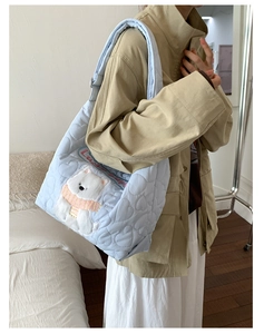 Détail du sac fourre-tout matelassé bleu clair avec motifs de cœurs et broderie d'ours