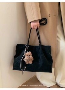 Detail of black matte tote bag featuring a cute plush bear charm and woven cord detail