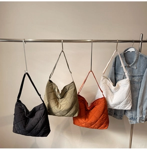 Detail view of quilted puffer tote bags in black, green, orange, and white on hangers
