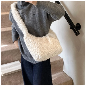 Close-up of white plush bucket bag with soft faux fur texture on woman's shoulder