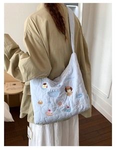 Vue détaillée d'un grand sac cabas matelassé bleu clair avec broderies chiots mignons
