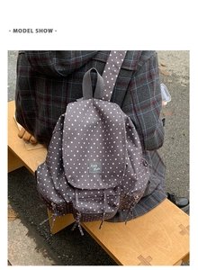 Detail of dark grey canvas backpack featuring white star patterns and a side pocket view