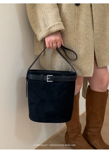 Sac seau chic en daim noir porté avec un manteau pour un style rétro minimaliste et sophistiqué
