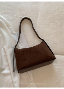 Detail of vintage brown suede leather bag with silver buckle on minimalist bedding