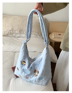 Détail du sac fourre-tout matelassé bleu clair avec motifs de cœur et broderie de chiot