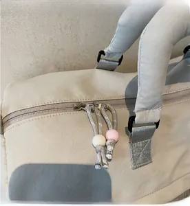 Détail d'une double fermeture éclair avec perles et broderie logo sur le sac de voyage