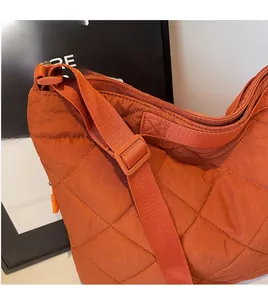Detail of orange quilted tote bag featuring classic diamond stitching and adjustable strap