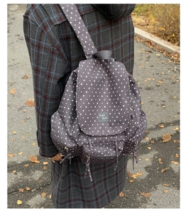 Detail of grey canvas backpack with white star pattern worn by model on autumn street