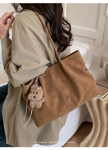 Macro detail of brown frosted suede tote bag with a cute plush bear pendant
