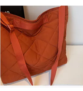 Close-up of reinforced stitching and quilted pattern on a large orange-brown tote bag