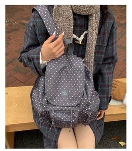 Outdoor model display of a grey canvas backpack with white star patterns and front pocket