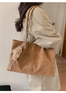 Macro shot of retro brown leather tote bag texture with cute plush bear keychain charm