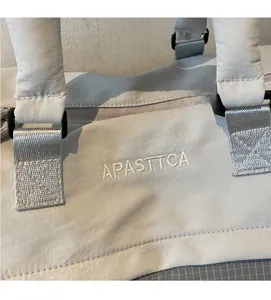 Vue détaillée du sac de voyage en nylon gris avec broderie APASTTCA et boucle de sangle