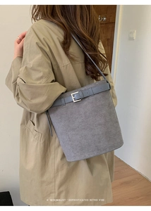 Détail du sac seau en daim gris avec garniture en cuir bleu et boucle argentée