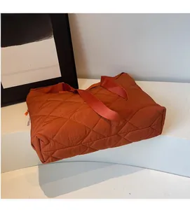 Detail of caramel quilted tote bag featuring large diamond stitching and wide straps