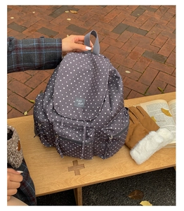 Detail of grey star-patterned backpack showing waterproof fabric and front zipper pocket