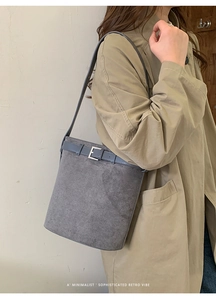 Détail du sac seau en daim bleu-gris avec bandoulière réglable et boucle en métal