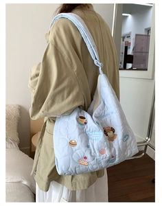 Détail du sac matelassé bleu clair avec broderie cartoon et large bandoulière