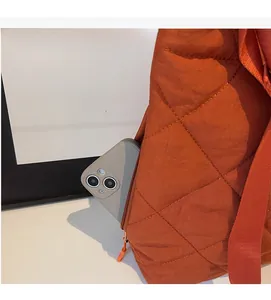 Detail view of a quilted orange tote bag featuring a functional side zipper pocket