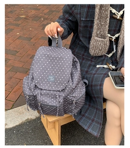 Close-up of star-print backpack showing front pocket, flap closure, and logo patch detail