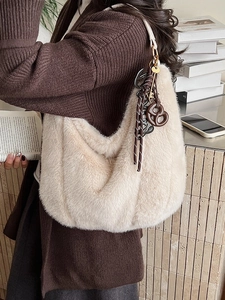 Plush off-white faux fur shoulder bag with woven knot charms for cozy autumn winter style