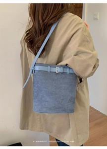 Détail du sac seau en daim bleu clair montrant la boucle métallique et la bandoulière