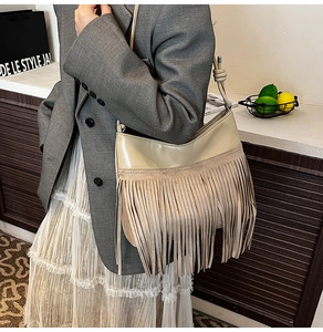 Dettaglio della borsa a tracolla beige con nappe, trame di pelle giuntate e tracolla annodata