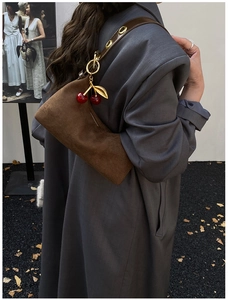 Detail of dark brown suede tote bag featuring a leather strap with gold metal eyelets