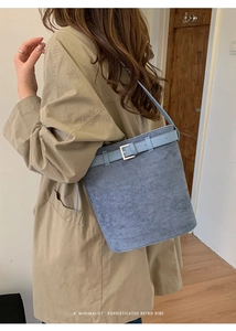 Sac seau bleu Morandi fini mat porté avec un trench beige pour un style vintage élégant