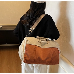 Détail du sac de voyage bicolore avec texture en nylon quadrillé et bandoulière