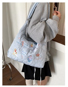 Gros plan du sac fourre-tout matelassé bleu clair avec broderies cartoon et motifs de cœur