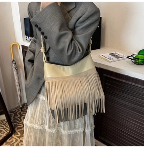 Dettaglio della borsa a secchiello boho retrò con nappe indossata con un outfit casual